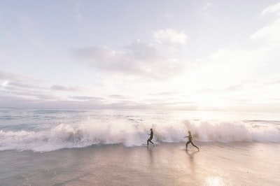 两个人白天在海边沙滩上跑步